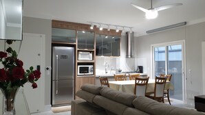 Una cocina moderna con electrodomésticos integrados, un comedor con mesa y sillas, y un ventilador de techo.