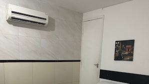 A hotel room with a bed, a wall-mounted air conditioner, a door, and a framed picture on the wall. - Flat boa viagem recife /PE (recife)