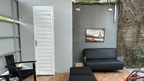 A room with a black sofa, a black chair, a white door, and a picture of the Eiffel Tower on the wall. - Flat boa viagem recife /PE (recife)