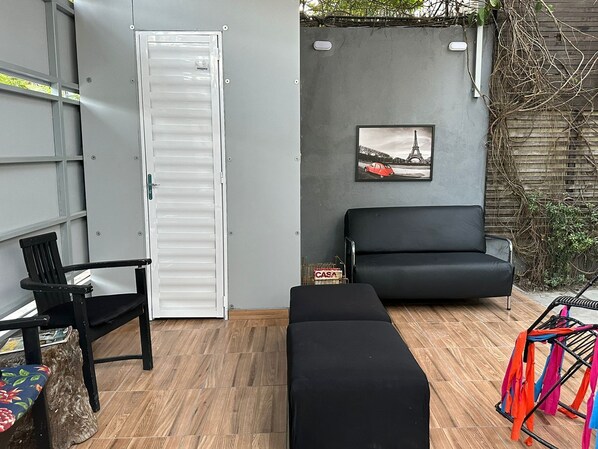 A room with a black sofa, a black chair, a white door, and a picture of the Eiffel Tower on the wall.