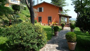 A house with a stone pathway leading to a covered porch with potted plants. - chaming little house with pool facing the most  beautiful tuscan scenary  (Lucca)