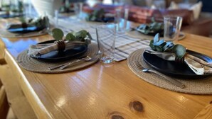 A wooden dining table set with plates, cutlery, and glasses, with a vase and greenery in the background. - Pearadise Peaks* Private Hot Tub, Wifi, 6Br, 3Ba (Island Park)