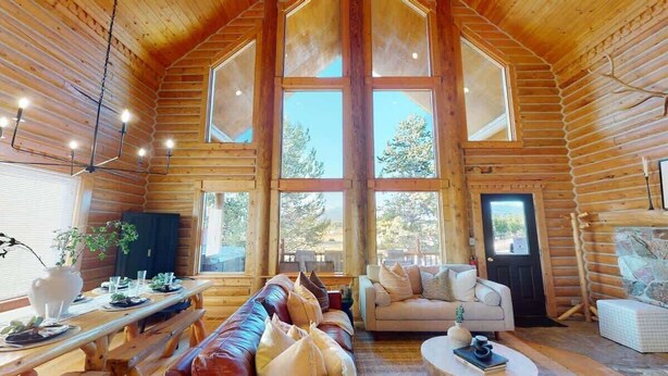 A log cabin interior with a large dining table, a sofa, and a fireplace. - Pearadise Peaks* Private Hot Tub, Wifi, 6Br, 3Ba (Island Park)