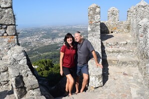 A couple standing in a stone structure with a view of a town and greenery below. - Private beachfront house with 400' dock, 2.5 acres, owners are nextdoor to help (Sandy Bay)
