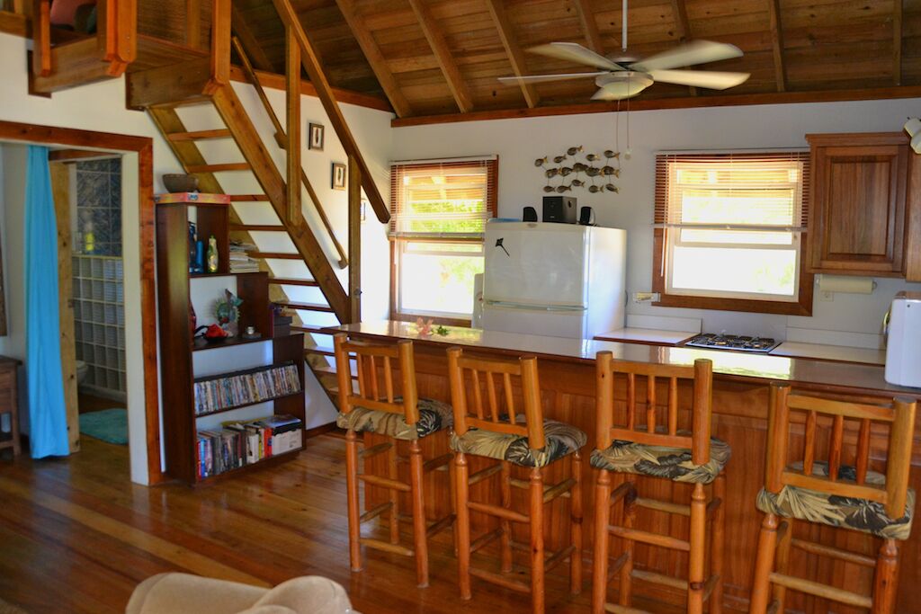 A kitchen with wooden chairs, a refrigerator, and a staircase.