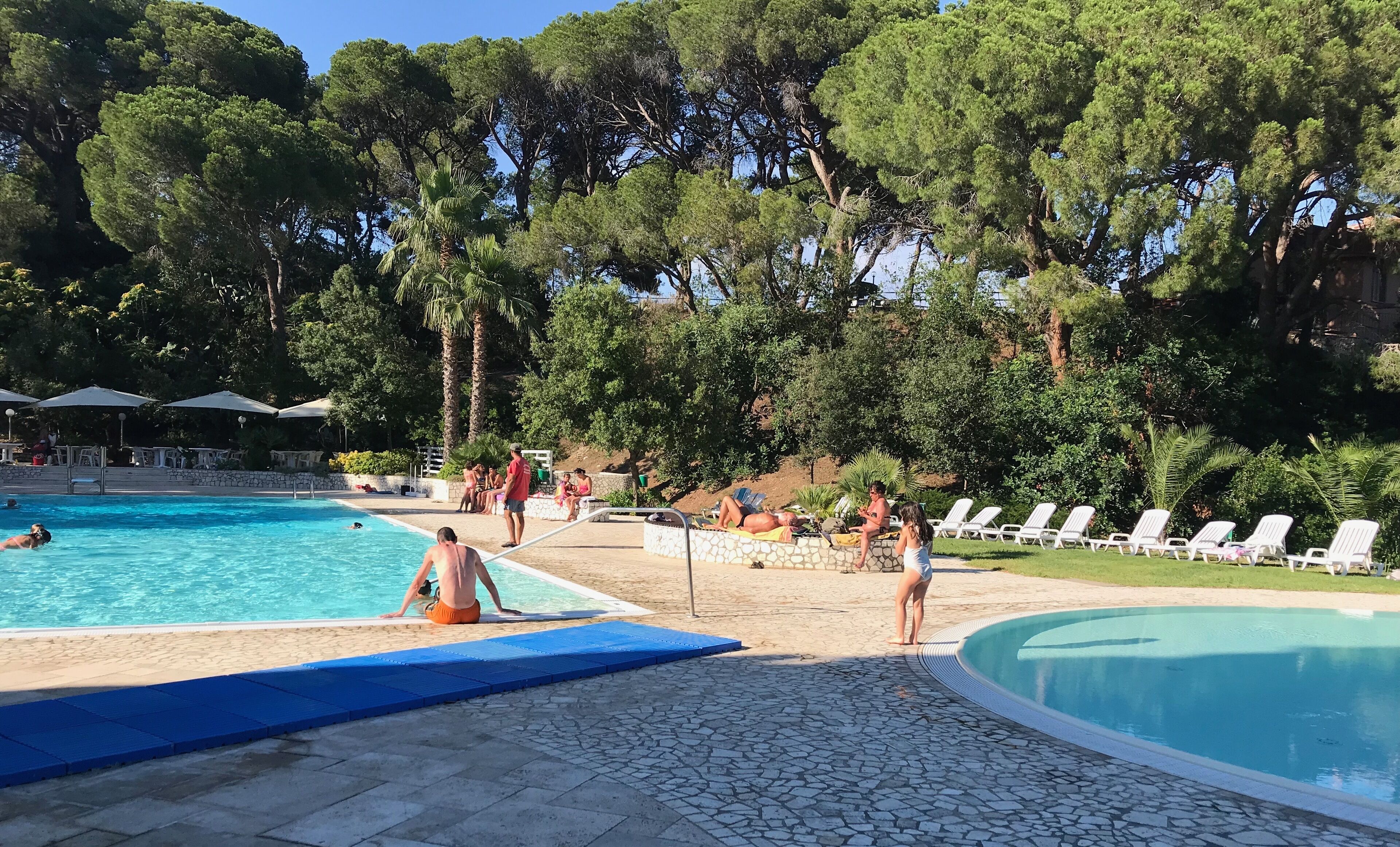 A pool area with multiple pools, lounge chairs, and a stone pathway.