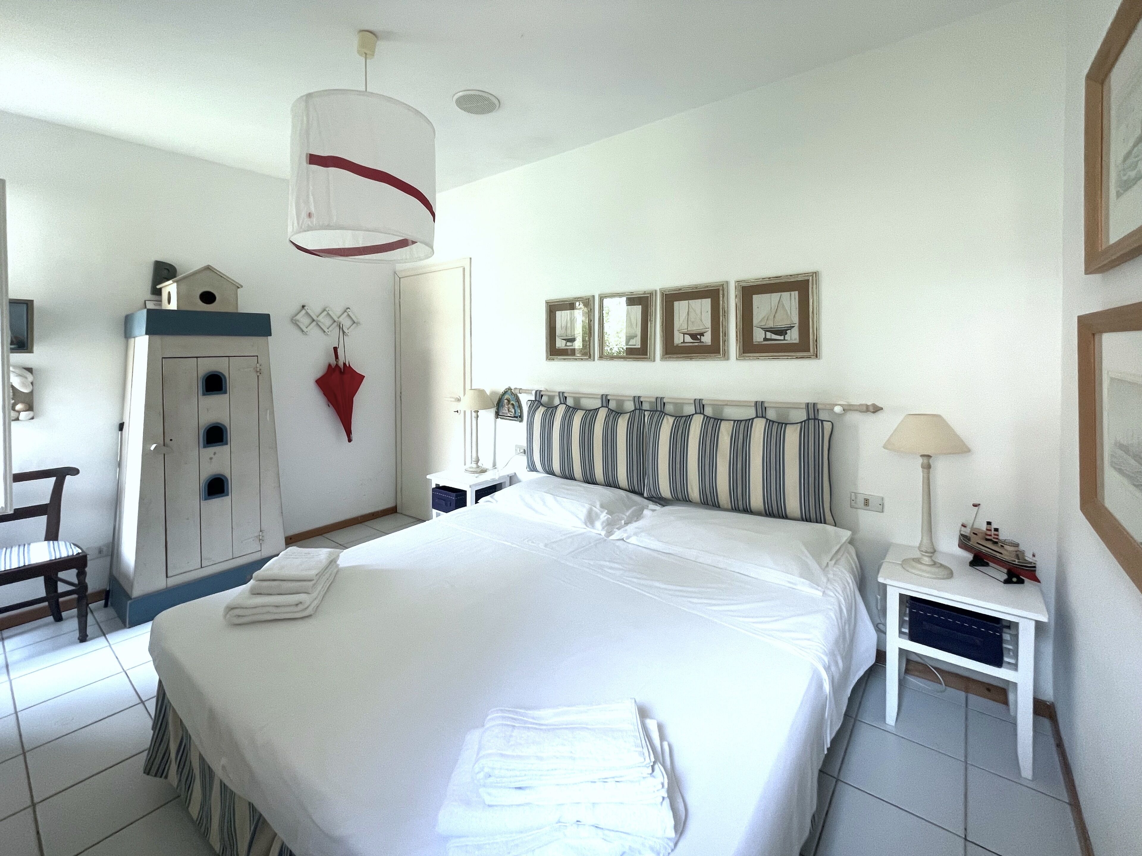 Habitación de hotel con una cama grande, un escritorio, una silla, un armario y una lámpara colgante.