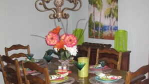 Una mesa de comedor con sillas, una araña y un cuadro en la pared.