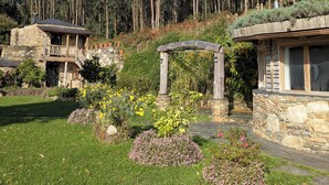 Een stenen huis met balkon en een tuin vol planten en bloemen.