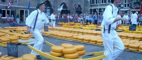 Un mercado de quesos con grandes ruedas de queso expuestas sobre mesas.