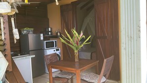Cocina compacta con zona de comedor, que incluye una mesa y sillas de madera, microondas y refrigerador.