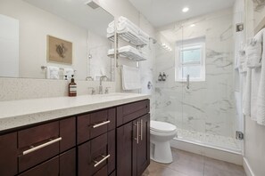 Features a sleek vanity, large mirror, and shower with glass door.