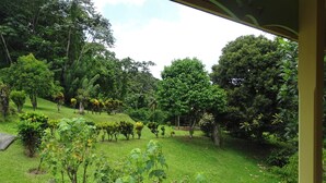 A lush garden with various plants and trees, a paved path, and a bench. - The Garden Cottage, a traditional island home in the heart of Martinique (Gros-Morne)
