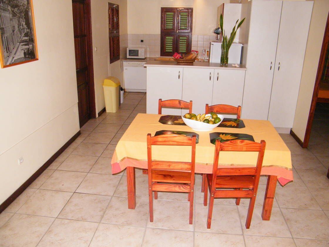 Un coin repas avec une table dressée pour quatre personnes, un four à micro-ondes, des placards et une poubelle.