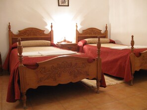 A bedroom with two wooden beds, each with a red bedspread and a wooden headboard.