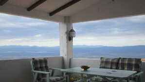 Een balkon met twee stoelen en een tafel, met uitzicht op een bergachtig landschap.