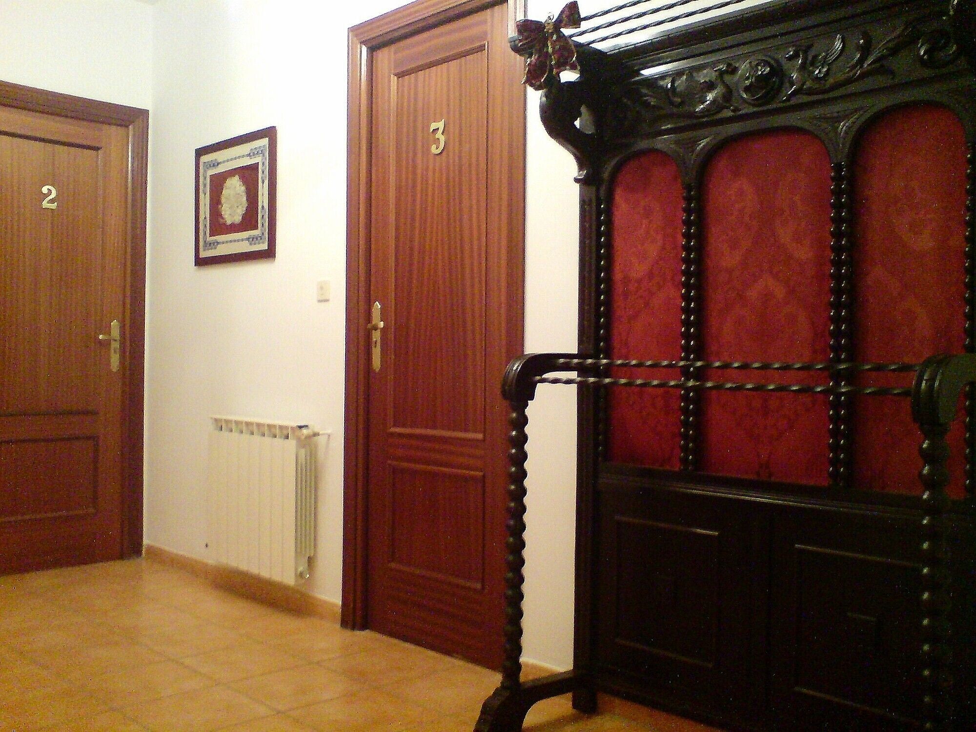 Un pasillo con dos puertas de madera, numeradas 2 y 3, y un radiador en la pared.