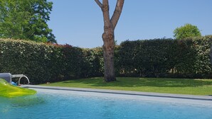 A swimming pool with a tree and hedge in the background. - House with private pool, in a quiet location close to Mimizan.  (Saint-Paul-en-Born)