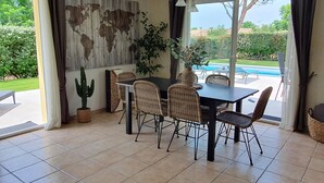 A dining area with a table and chairs, a cactus plant, and a guitar. - House with private pool, in a quiet location close to Mimizan.  (Saint-Paul-en-Born)