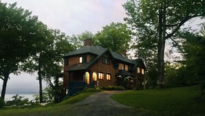 A large, two-story house with a stone facade, a prominent front porch, and a driveway leading to the entrance.