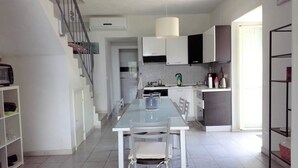 A modern kitchen with white cabinetry, a dining table with chairs, and a staircase. - House PANORAMIC VIEW SEA between SEA and MOUNTAIN  (Nocera terinese)
