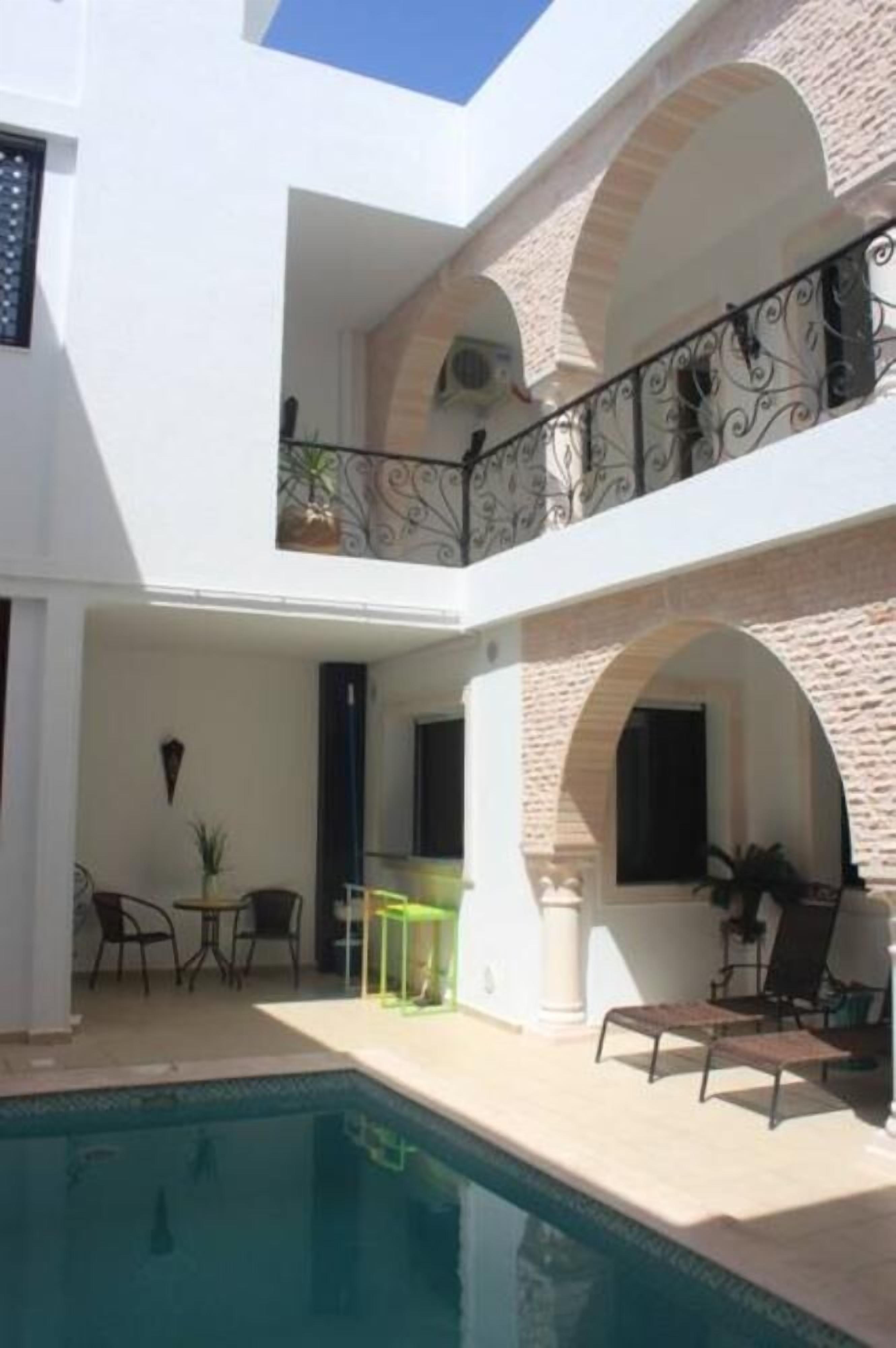 Edifici de dues plantes amb piscina, seients exteriors i un balcó amb barana decorativa.