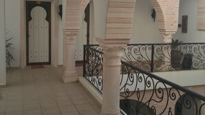 A covered outdoor area with tiled flooring, white walls, and arches.