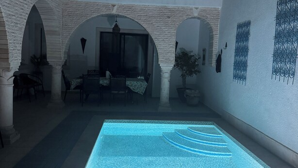 A spacious indoor pool area with a clear view of the pool, surrounded by white brick walls and arches.