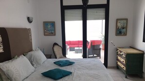 A bedroom with a bed, a chair, a dresser, and two paintings on the wall.