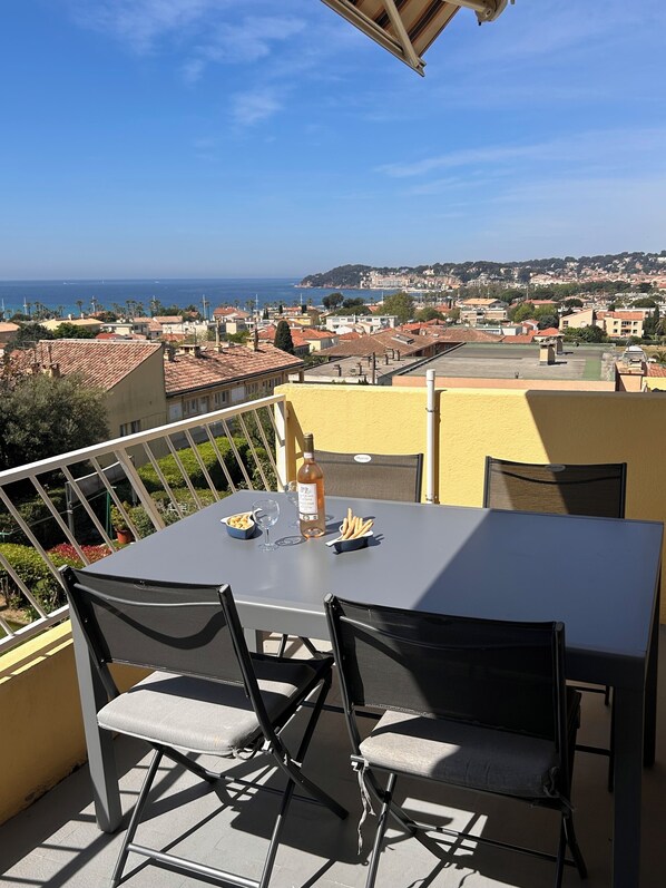 A balcony with a table set for two, overlooking a coastal town.