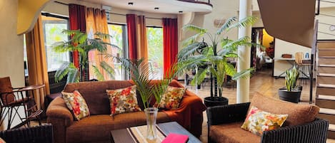 Amplia sala de estar con un conjunto de sofás, una mesa de centro y varias plantas en macetas.