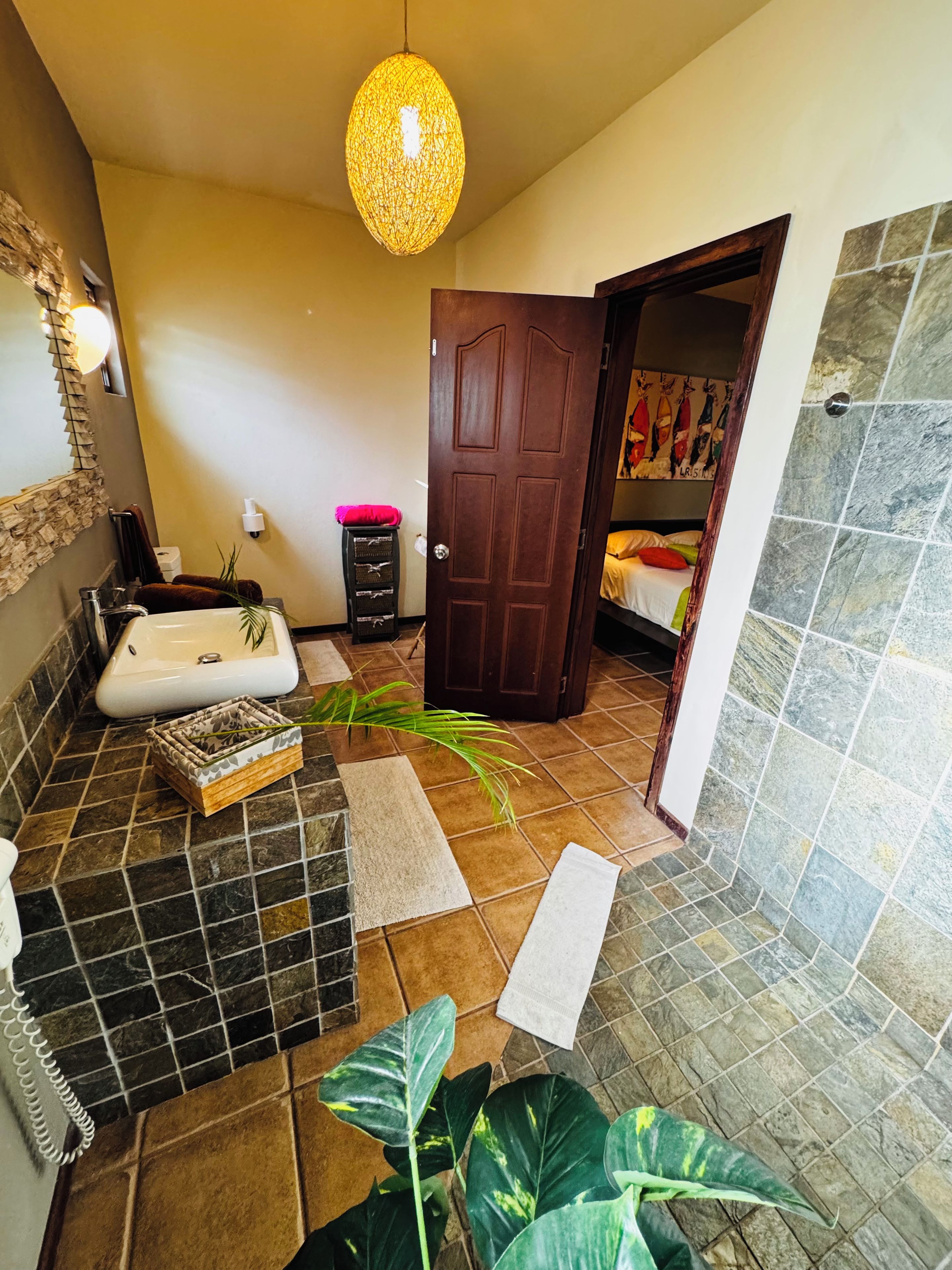 A bathroom with a bathtub, a sink, a mirror, and a door leading to a bedroom.
