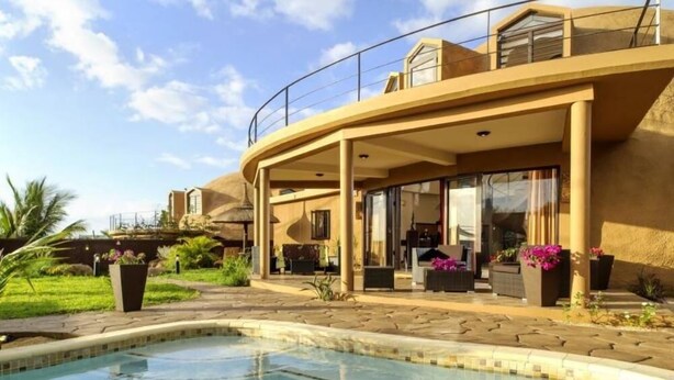 Une villa moderne dotée d’une piscine, d’un espace salon extérieur et d’un patio couvert.