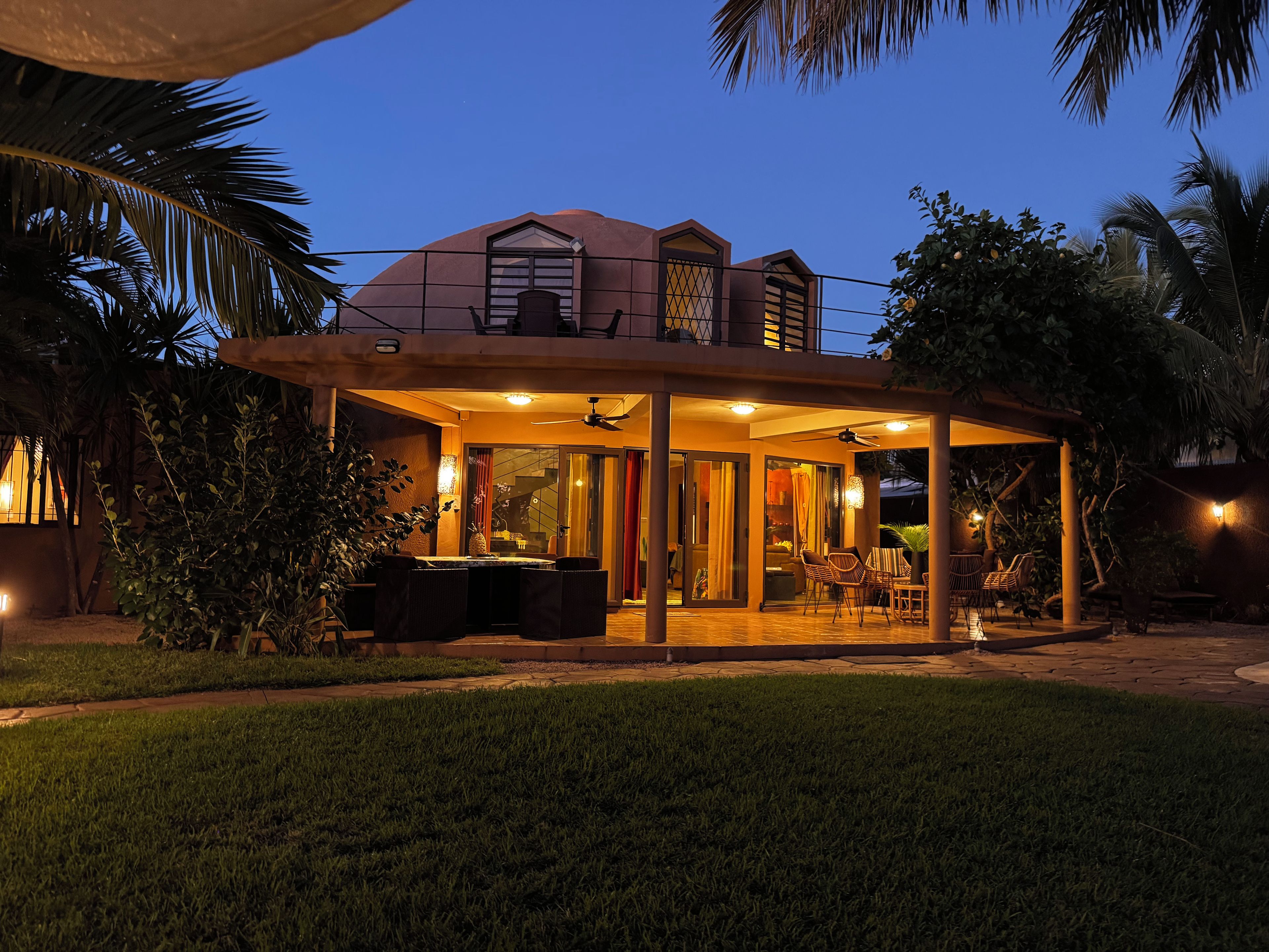Ein Haus mit überdachter Terrasse, Sitzgelegenheiten im Freien und einem Pool.