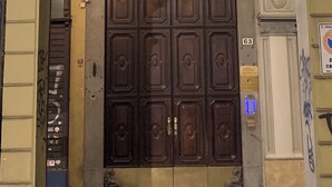 Una puerta de madera grande y ornamentada con un tragaluz encima, ubicada en un arco de piedra.