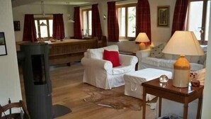 Una sala de estar acogedora con chimenea, un sofá, una mesa con lámpara y piso de madera.