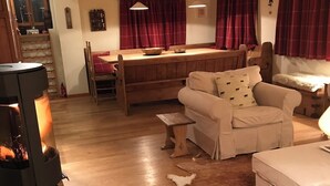 Una sala de estar acogedora con chimenea, muebles de madera y un comedor con cortinas rojas.