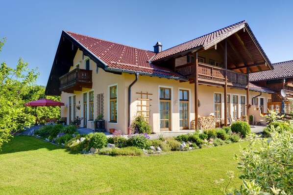 A two-story house with a sloped roof, wooden balconies, and a well-maintained garden.