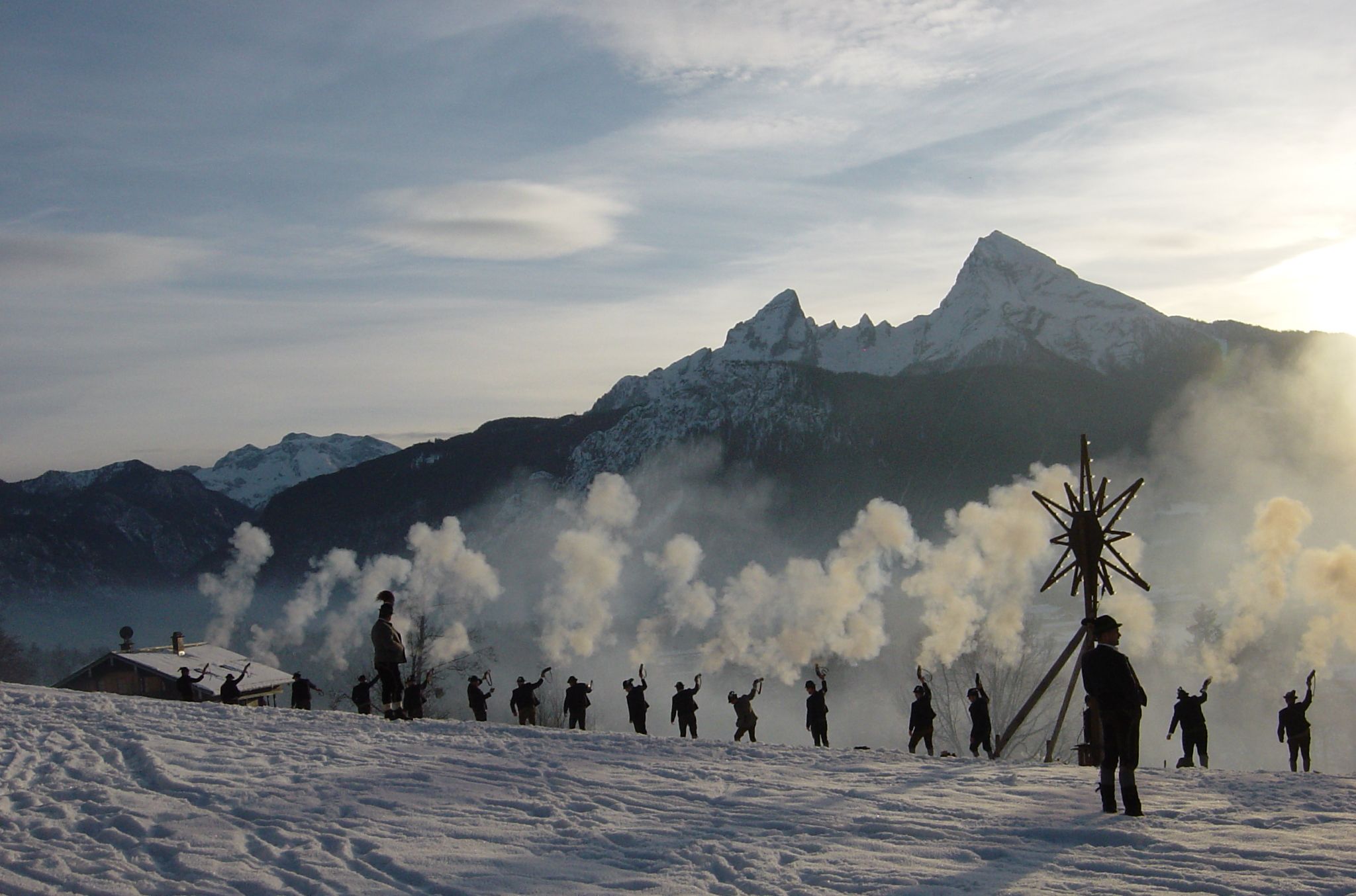 Un paysage montagneux enneigé avec un groupe de personnes et une grande structure en forme d’étoile.