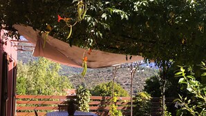 Un patio al aire libre con una mesa y sillas, rodeado de plantas en macetas y una valla de madera.