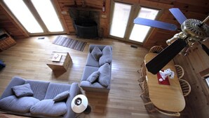 A cozy cabin interior with a sofa, a dining table, and a ceiling fan. - Valley View Cabin with show-stopping vaulted ceilings!  (Hico)