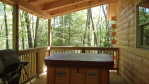 A wooden deck with a hot tub, a grill, and a view of a forest. - Valley View Cabin with show-stopping vaulted ceilings!  (Hico)