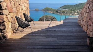 A wooden deck with a stone wall on one side and a metal railing on the other, overlooking a coastal view with clear blue waters and distant hills. - Luxury villa 5 * panoramic sea view private heated pool + SPA (Conca)