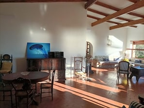 Amplia sala de estar con techo de madera, una mesa redonda y varias sillas.