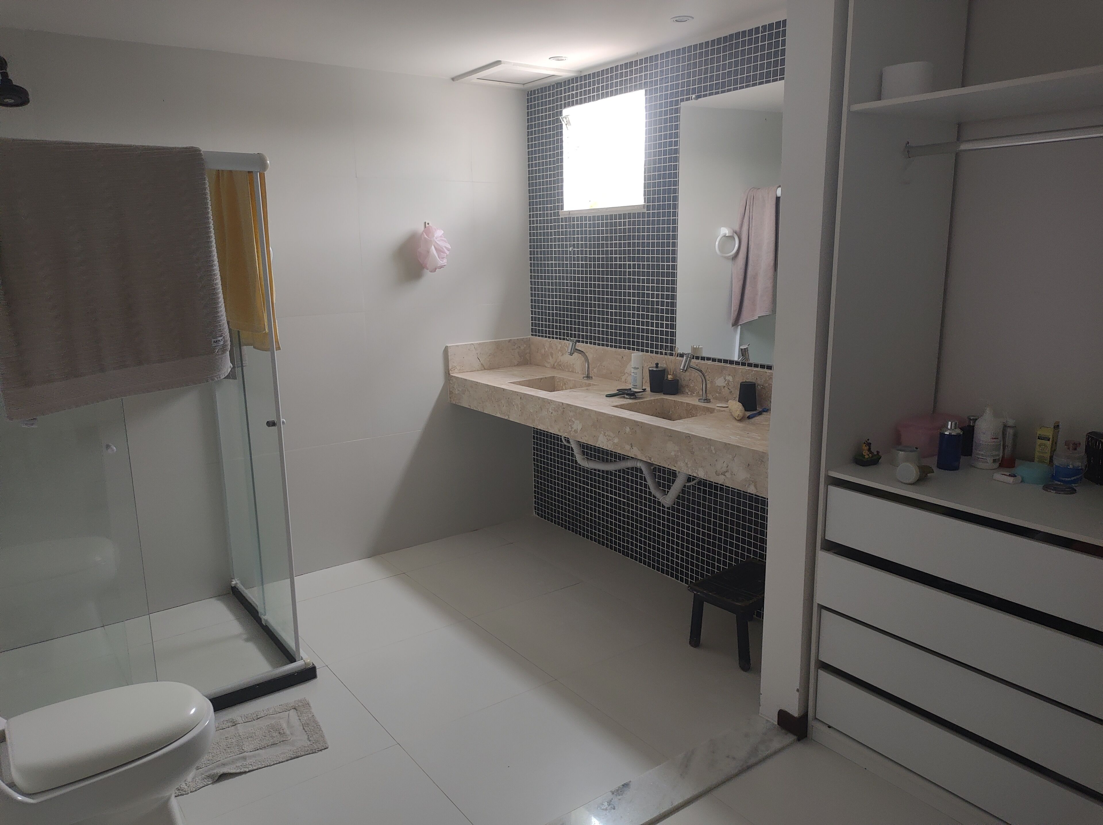 A bathroom with a toilet, a sink with a mirror, and a shower area.