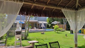 A covered outdoor area with a pool, lounge chairs, and a barbecue grill. - Home. Spectacular, 5 Suites, High Standard, ITACIMIRIM. CONDITION QUINTA DAS LAGOAS.  (Camaçari)