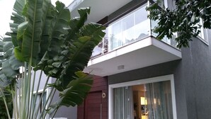 A modern two-story building with a balcony, large windows, and a small outdoor seating area. - Home. Spectacular, 5 Suites, High Standard, ITACIMIRIM. CONDITION QUINTA DAS LAGOAS.  (Camaçari)