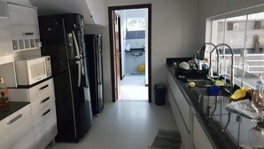 A modern kitchen with a refrigerator, microwave, and sink. - Home. Spectacular, 5 Suites, High Standard, ITACIMIRIM. CONDITION QUINTA DAS LAGOAS.  (Camaçari)