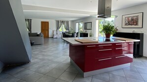 Un'ampia cucina con isola centrale, un'area pranzo e un soggiorno con divano e tende.