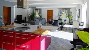 Una cucina moderna con armadietti rossi, un'isola centrale e un'area pranzo con divano e sedie.